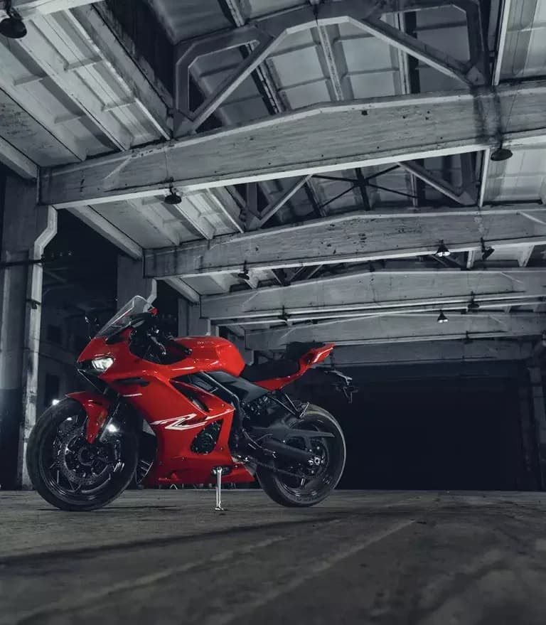 Motocicleta KOVE deportiva roja de perfil en una nave industrial abandonada con vigas de hormigón y luz cenital
